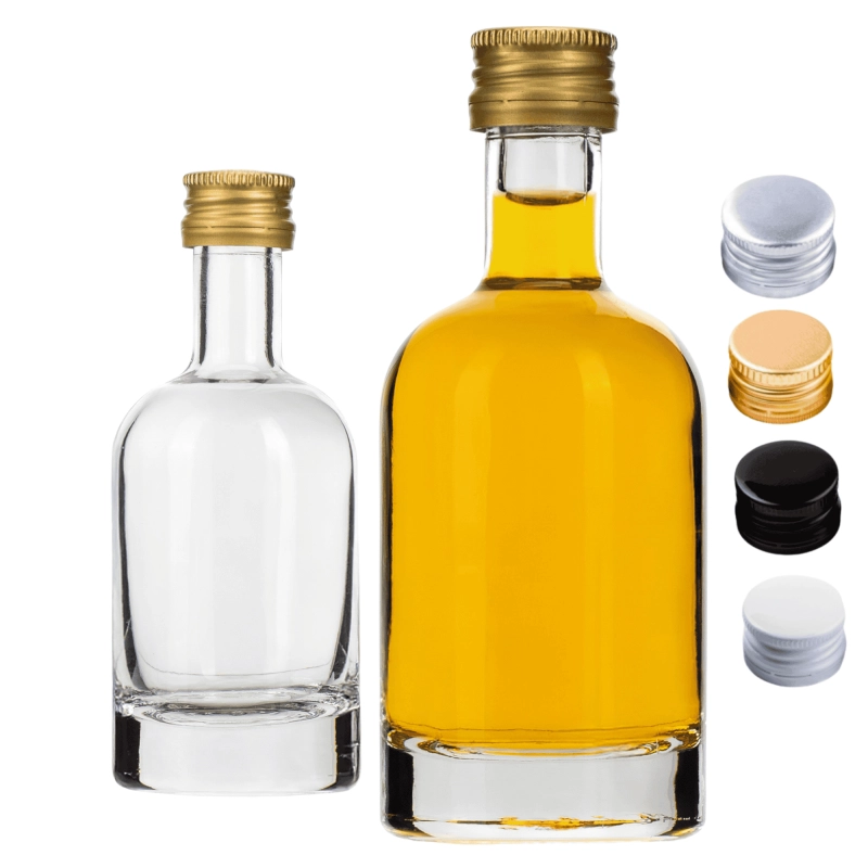 Cytrynówka w szklanej buteleczce Tadek 50 ml na kuchennym blacie obok szklanki z sokiem