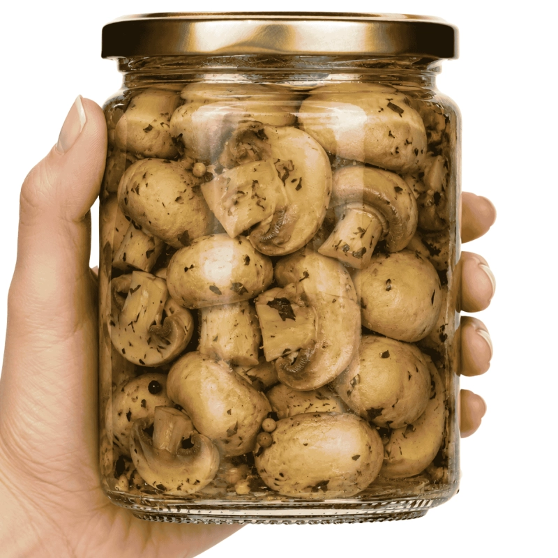 Dłoń trzymająca słoik szklany Simple 540 ml z marynowanymi pieczarkami, rozmiar porcji obiadowej dla rodziny