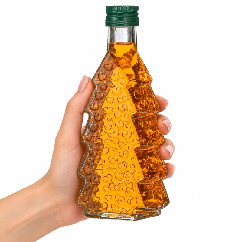 Szklana choinka 250 ml z bursztynowym płynem trzymana w dłoni, gruba butelka na nalewki i likiery